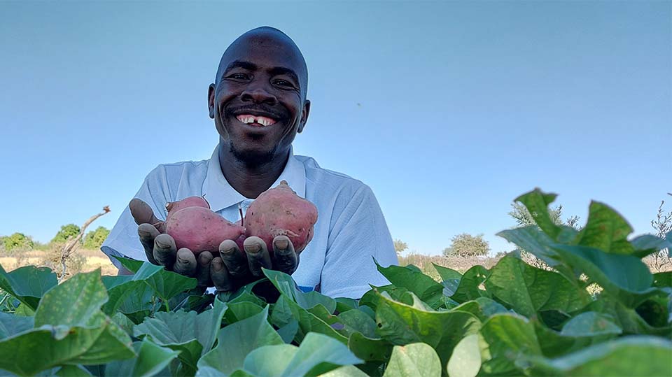 Sudanese community extension worker holding crops