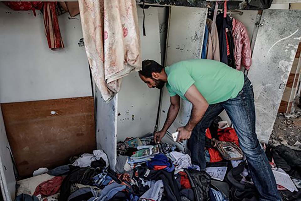 man stands removes belongs from a home destroyed in Gaza