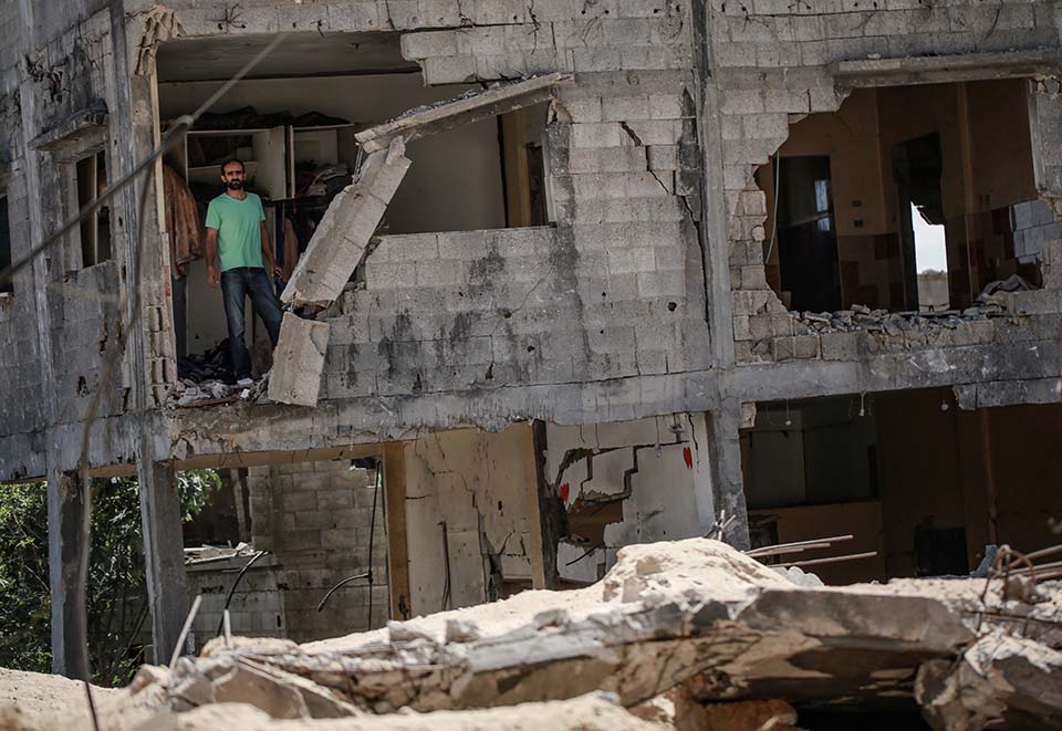 man stands in remains of home destroyed in Gaza