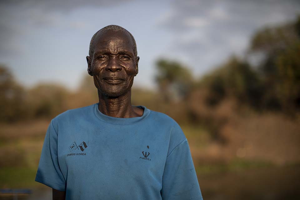South Sudanese vegetable farmer tands in a field prepared for use