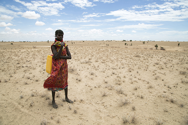 Woman stands in parched Kenya landscape