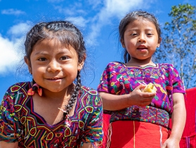  Two little girls wearing colorful dresses smile at the camera