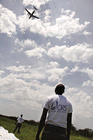 A CRS staffer looks on as food from the World Food Programme is airdropped in South Sudan. CRS is distributing the food to 100,000 people. Photo by Donal Reilly/CRS
